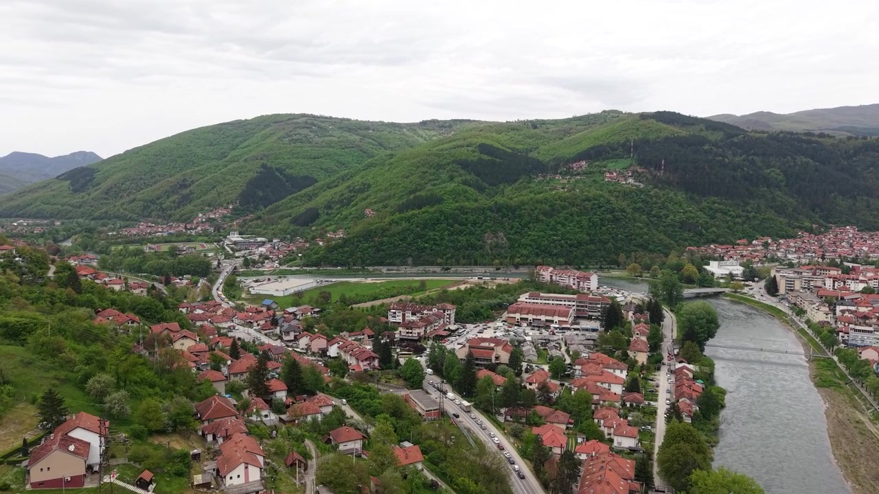 Sırbistan, Prijepolje'den drone çekimi. Lim Nehri kenarında küçük kasaba, yeşil tepelerin altında trafik ve binalar.