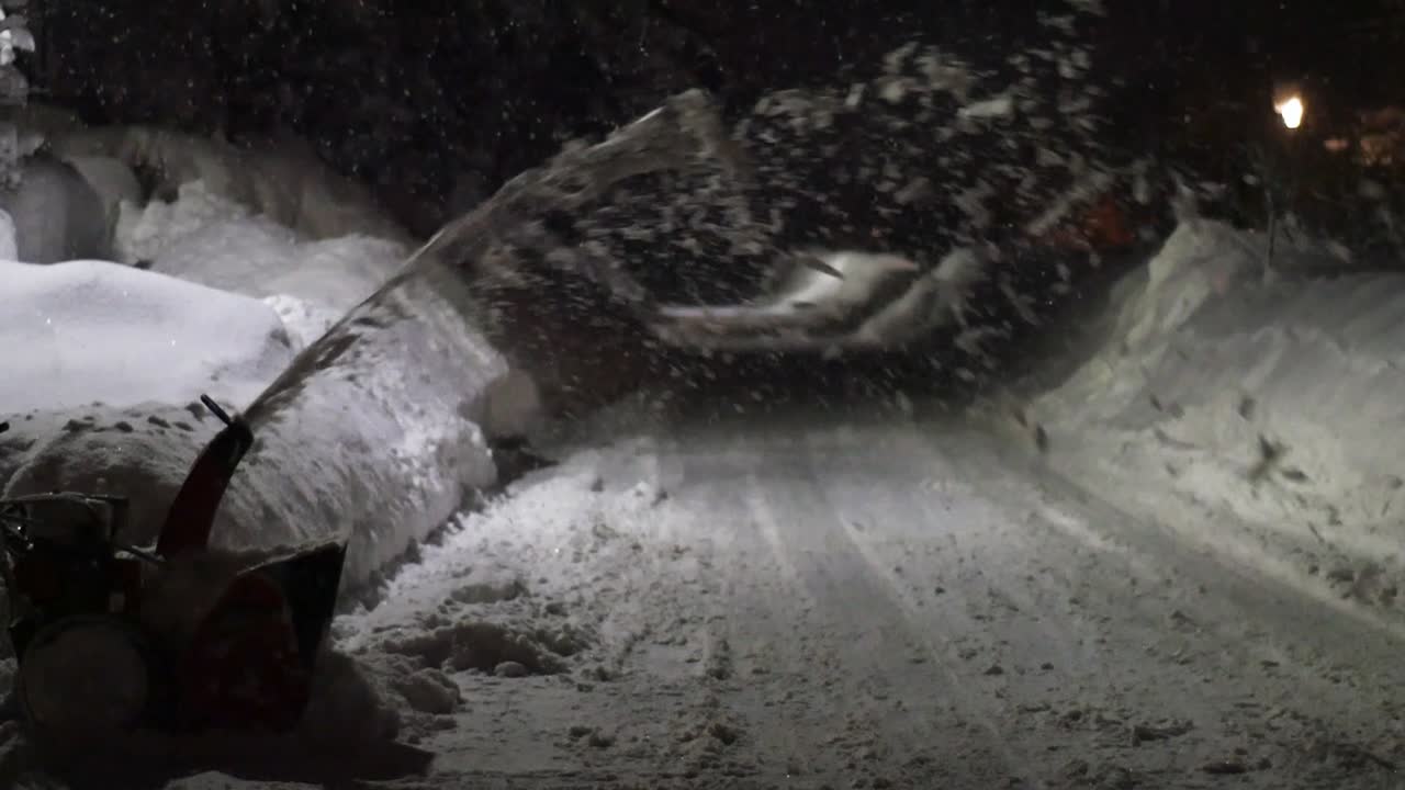 quitanieves soplando nieve en una vía pública durante la noche