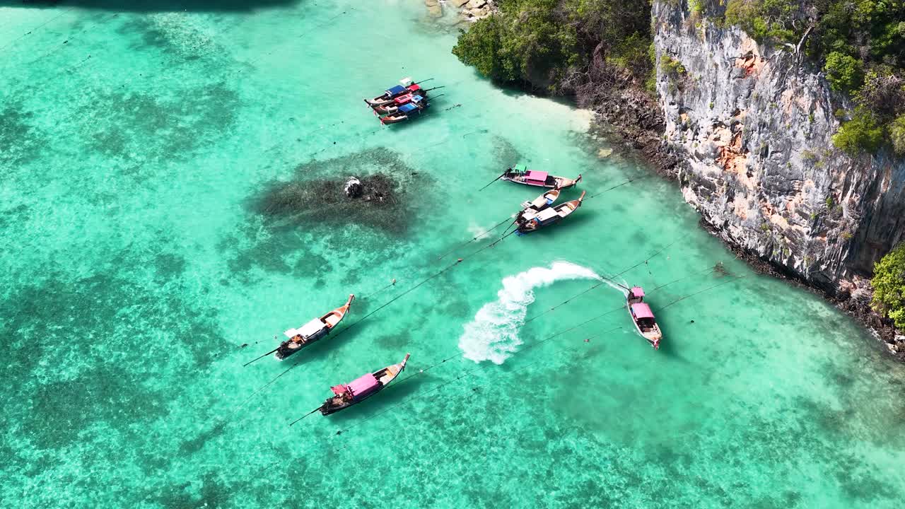 Foto aerea dall'alto di tradizionali barche longtail che galleggiano in acque cristalline turchesi tropicali