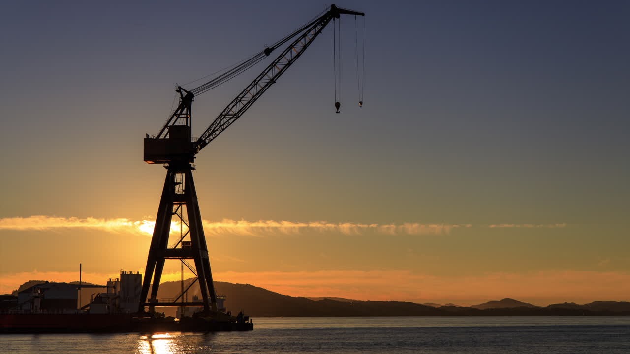 puesta de sol detrás de una gran grúa industrial vintage