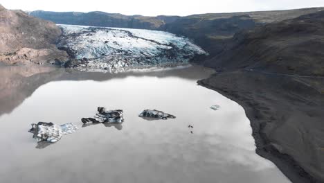 Kayakers-kayaking-in-muddy-lake-with-ice-in-Solheimajokull-glacier