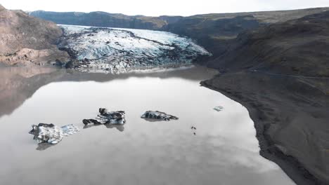 kayakers kayaking in muddy lake with ice in solheimajokull glacier