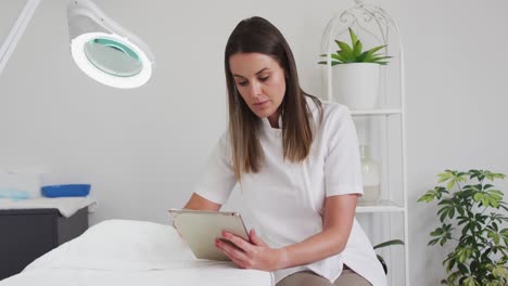 caucasian female beautician using digital tablet in beauty salon