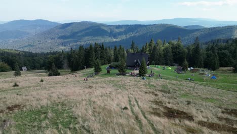 Mountain-shelter-during-a-summer-day-with-mountains-peaks,-forest,-lush-greenery-and-trees