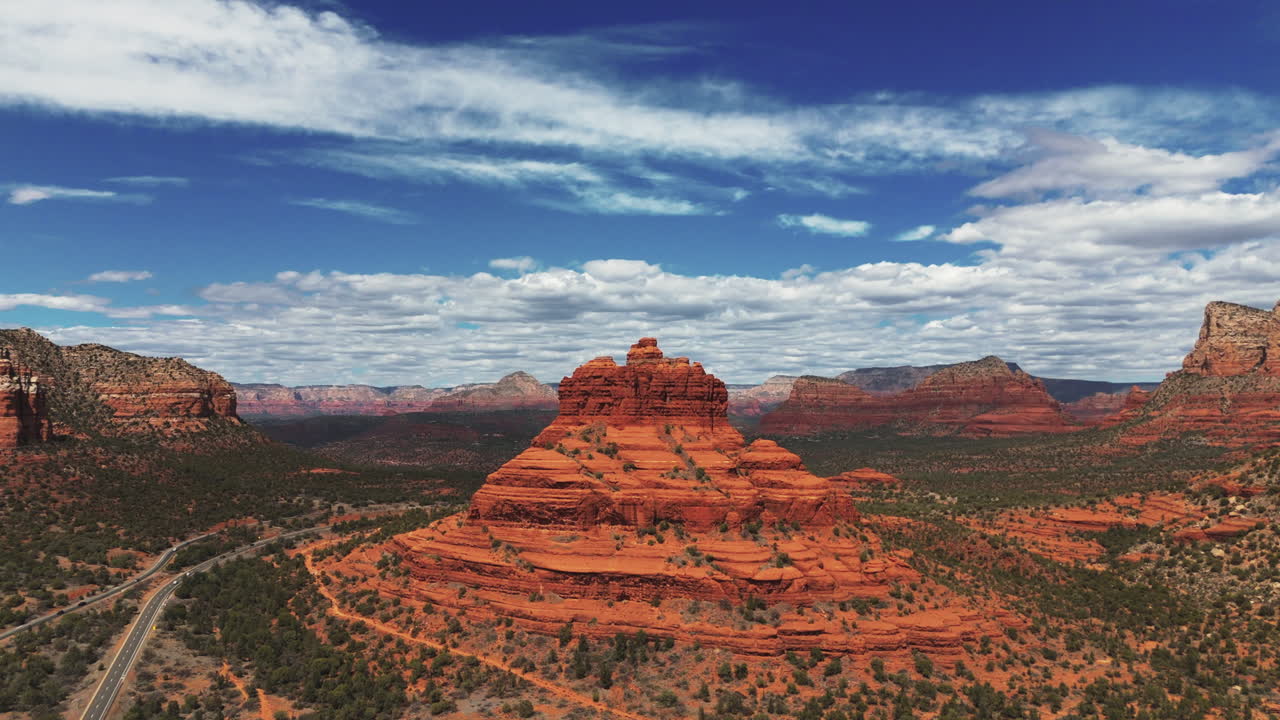 Cars Driving Through The Road Passing By Bell Rock Butte In Sedona, Arizona, USA. - aerial shot