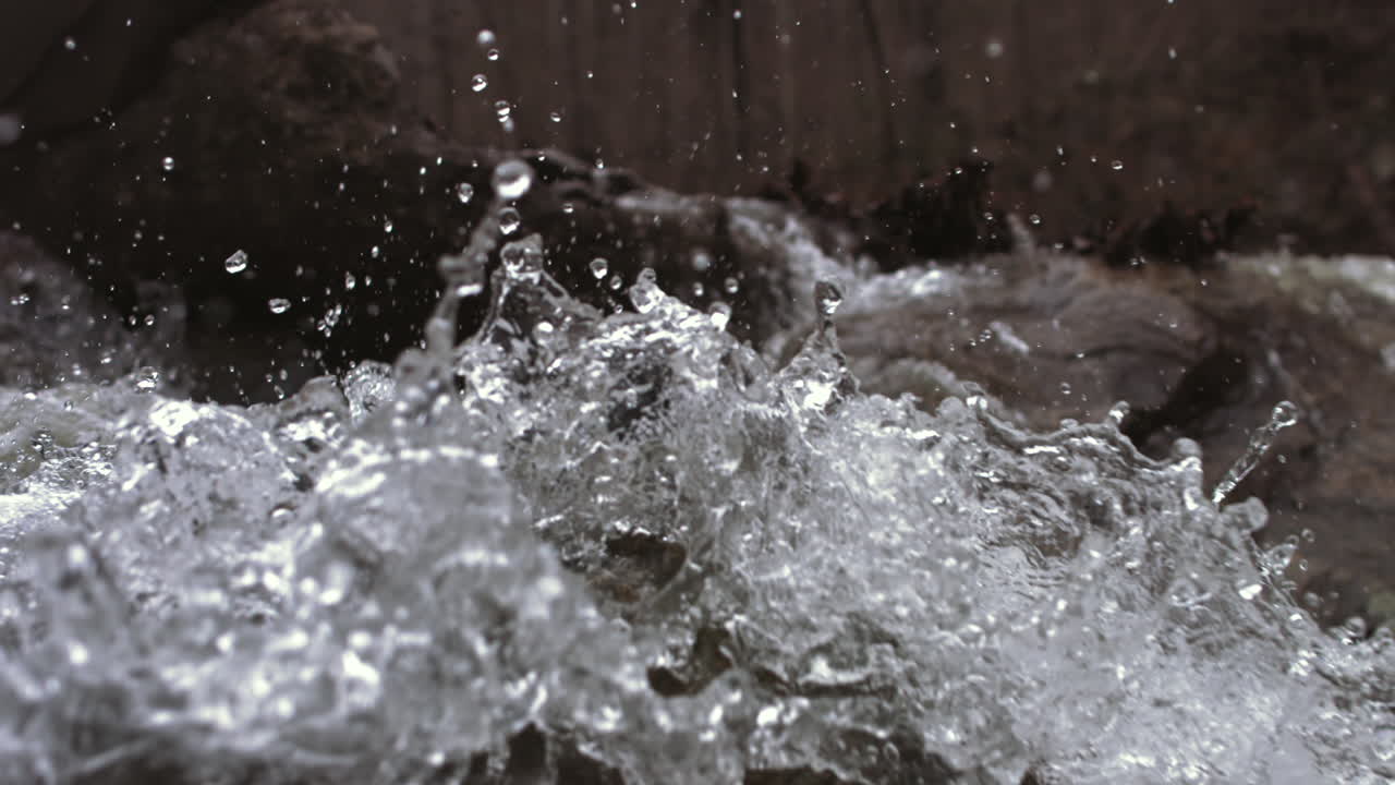 Super slow motion droplets of water crashing off rocks in a river and flying into the air.