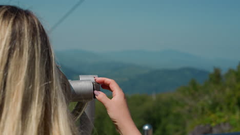 lady turns wheel to adjust tower viewer and enjoy landscape