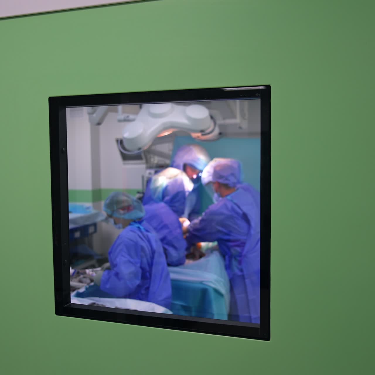 Little square window in the doors to the surgical theatre. Medical team of surgeons working inside the operational theatre