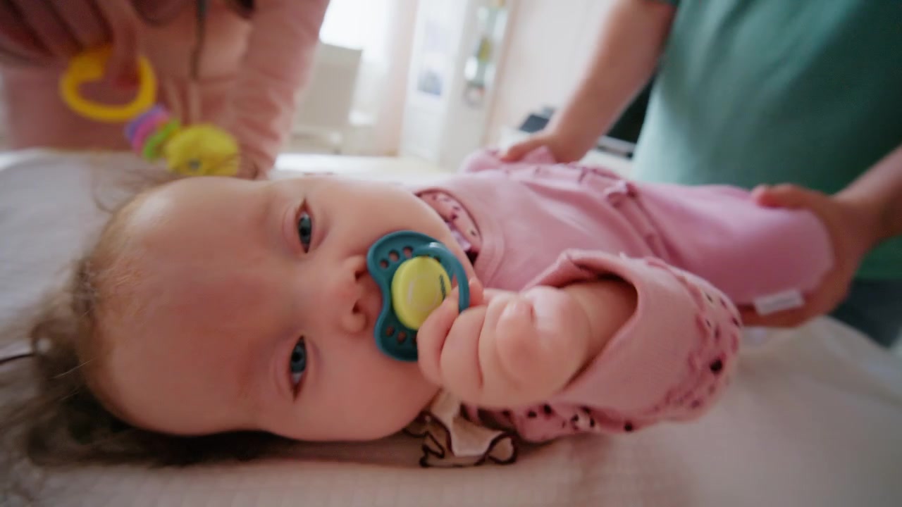 Baby lying on a treatment table with a pacifier while adults provide gentle support during a pediatric therapy session