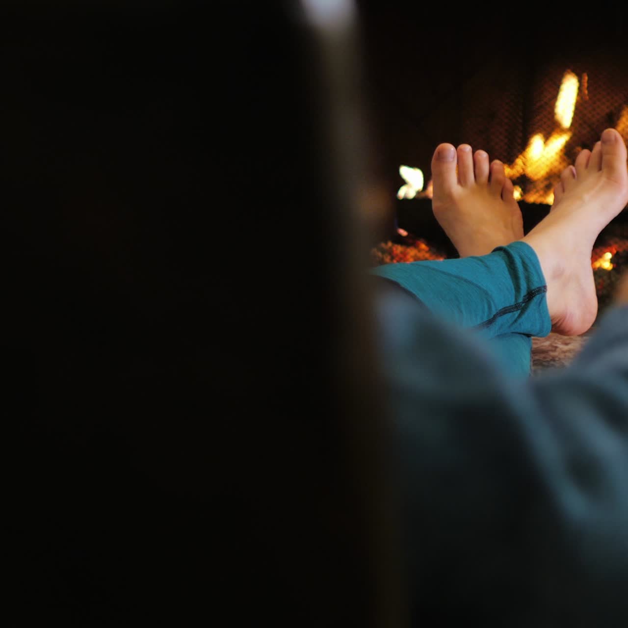 벽난로 옆에 앉아 와인 한 잔을 들고 있는 남자가 발을 따뜻하게 합니다 2