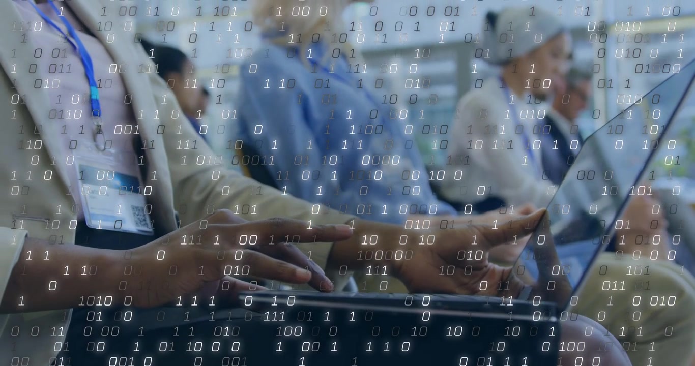 Binary overlay forming, causing attendee hands and laptop typing and tilting, showing data flow