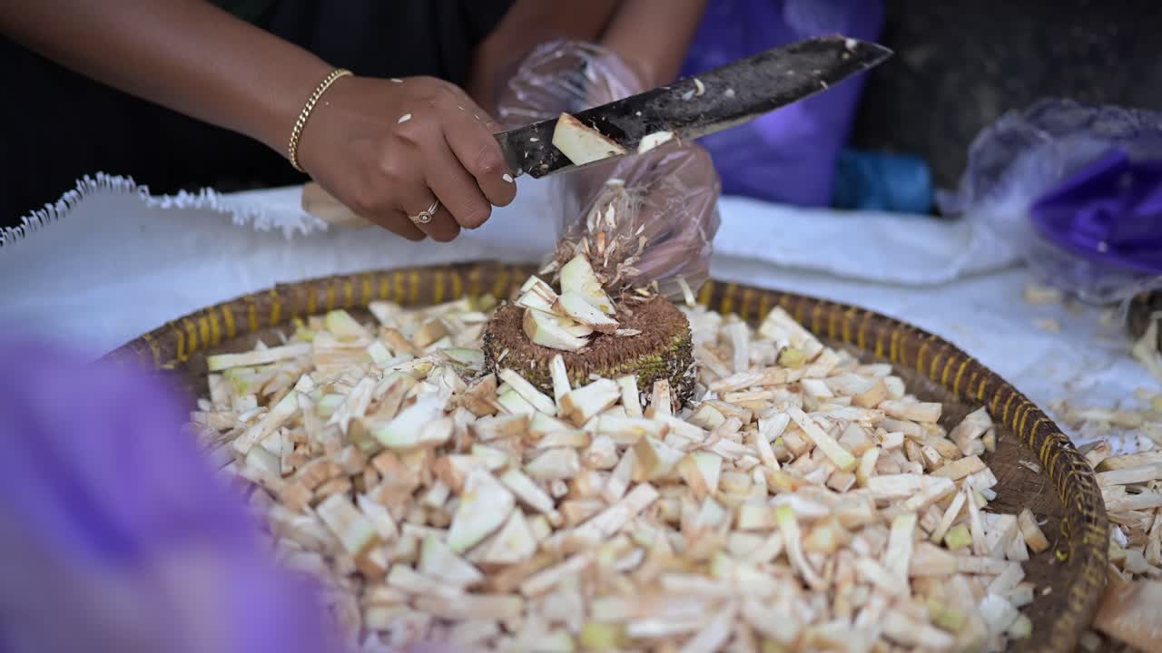 Primo piano del processo di persone che preparano cibo da pezzi di giovane jackfruit in un mercato tradizionale.