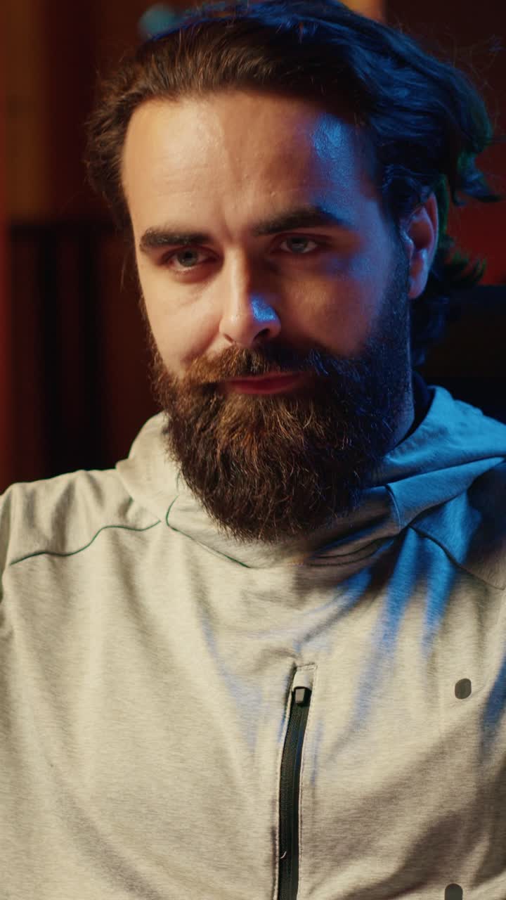 Сфокусированный мужчина, снимающий вертикальное видео в гостиной, освещенной RGB-лампами, играет в видеоигры