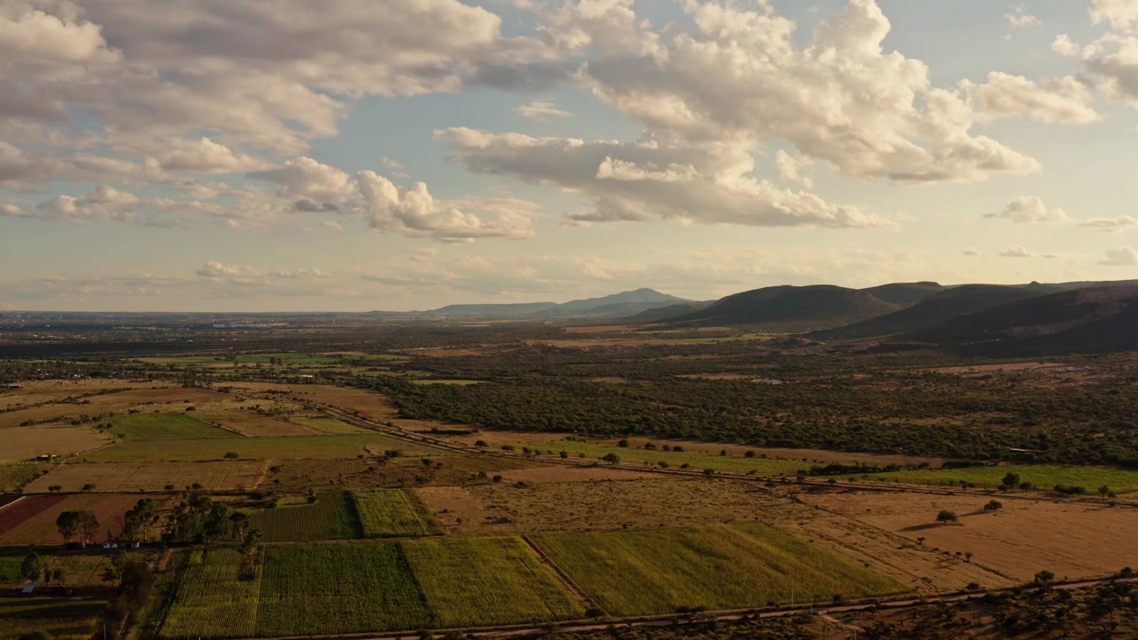 Paisaje rural ondulado con campos y cielo nublado que se extiende por el horizonte, vista general aérea de dron