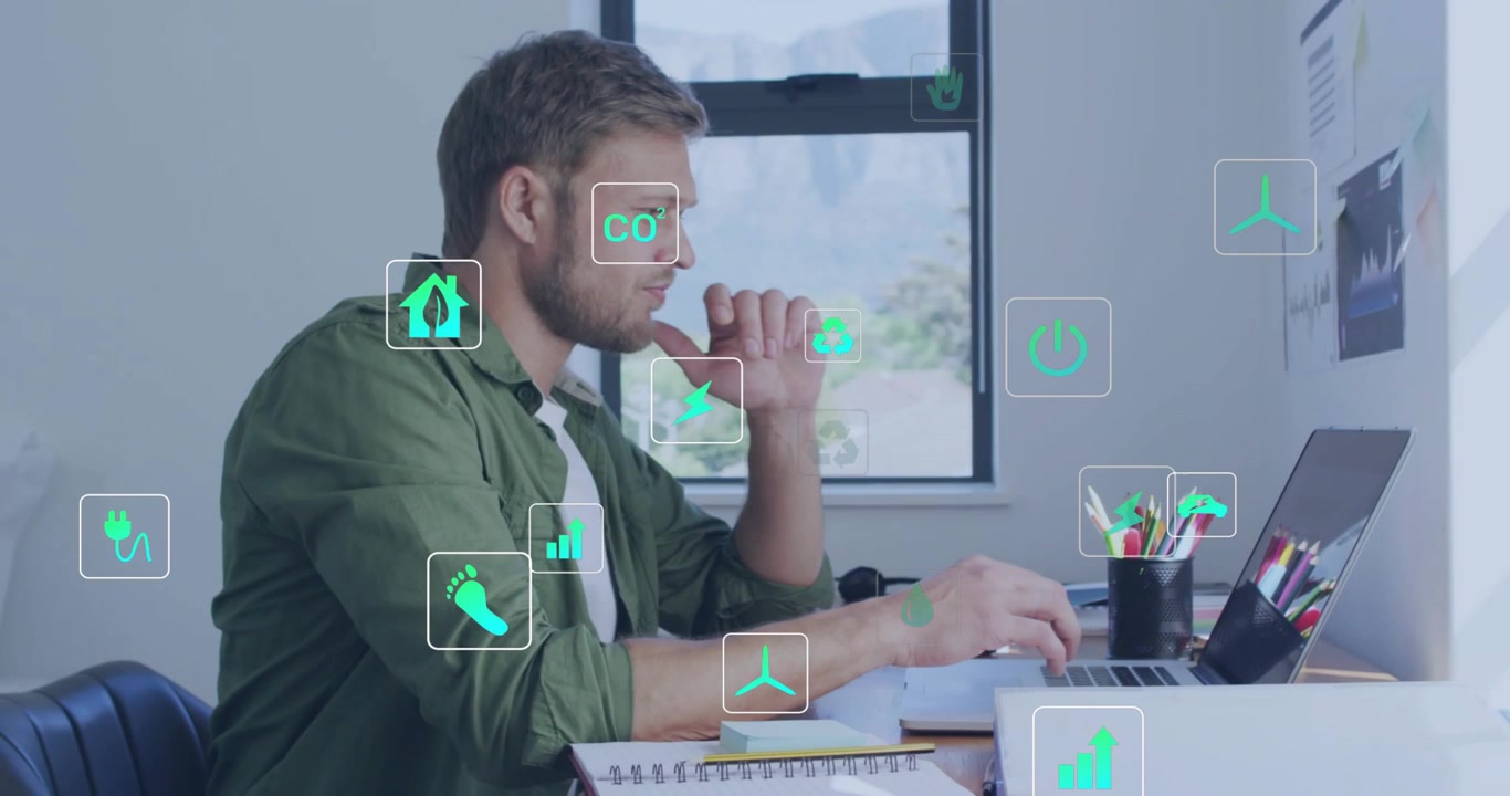Man typing at laptop and reaching for pen, activating green energy icons while analyzing charts