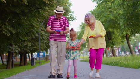 Smiling-senior-grandmother-grandfather-with-granddaughter-playing-squeezing-anti-stress-toy-game