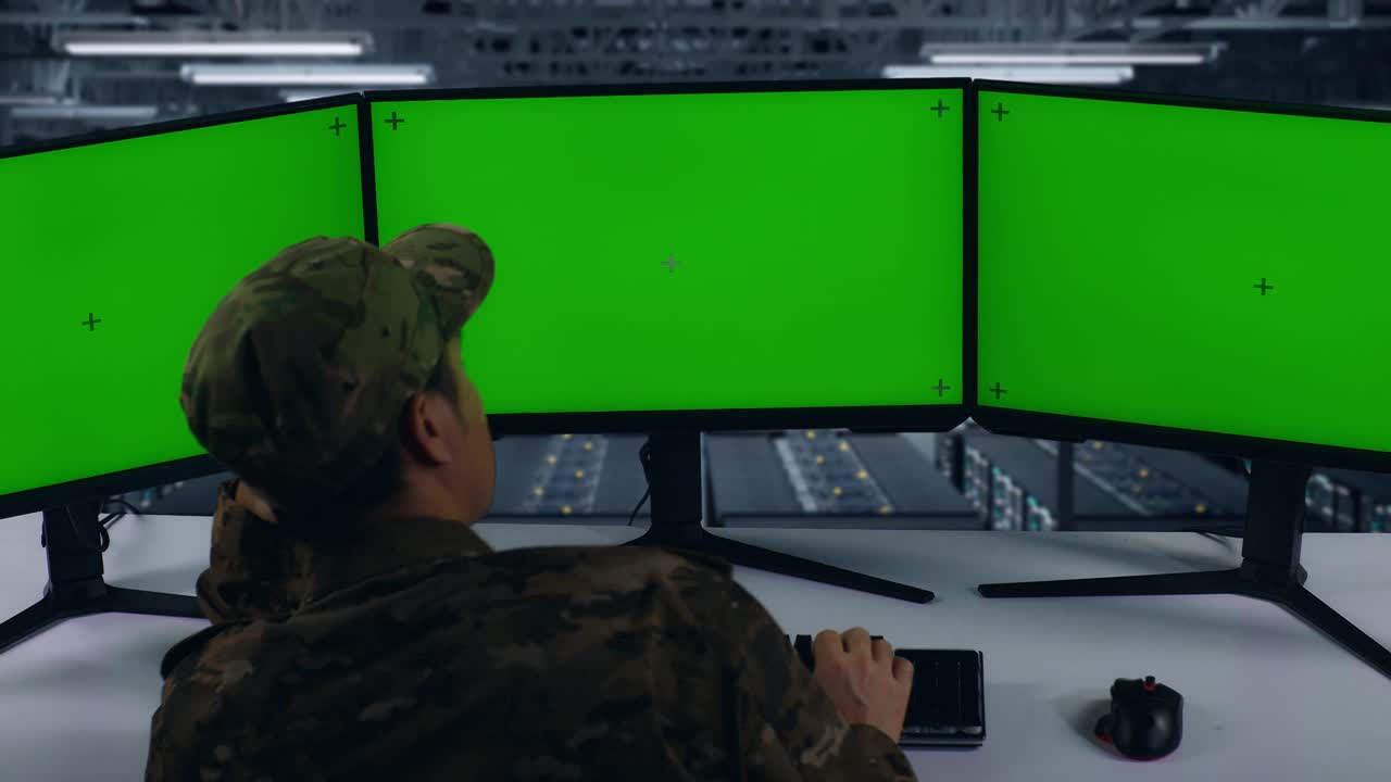 vista de atrás de los militares asiáticos aburridos trabajando con simulacros de múltiples monitores de computadora en el centro de datos