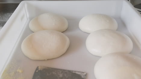 close up view of balls of pizza dough on a tray in a restaurant kitchen