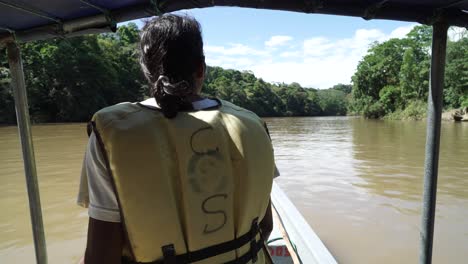 Guía-Turístico-Masculino-Sentado-En-Un-Barco-Turístico-Tradicional-Navegando-Rápido-A-Través-De-Un-Ancho-Río-En-Ecuador