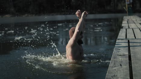 Hombre-Adulto-Caucásico-Saltando-A-Un-Lago-Congelado-Desde-El-Muelle-En-Invierno.