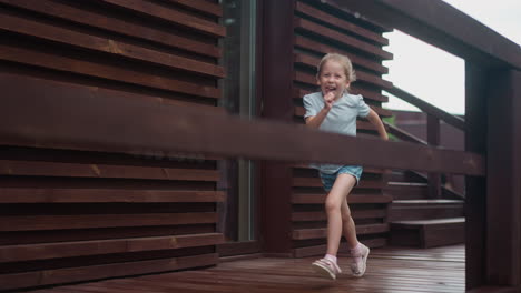 Little-girl-runs-having-fun-along-veranda-deck-at-cottage