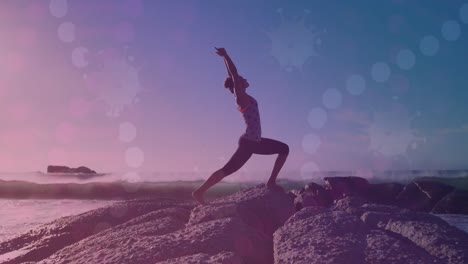 animación de luces brillantes sobre una mujer biracial practicando yoga junto al mar