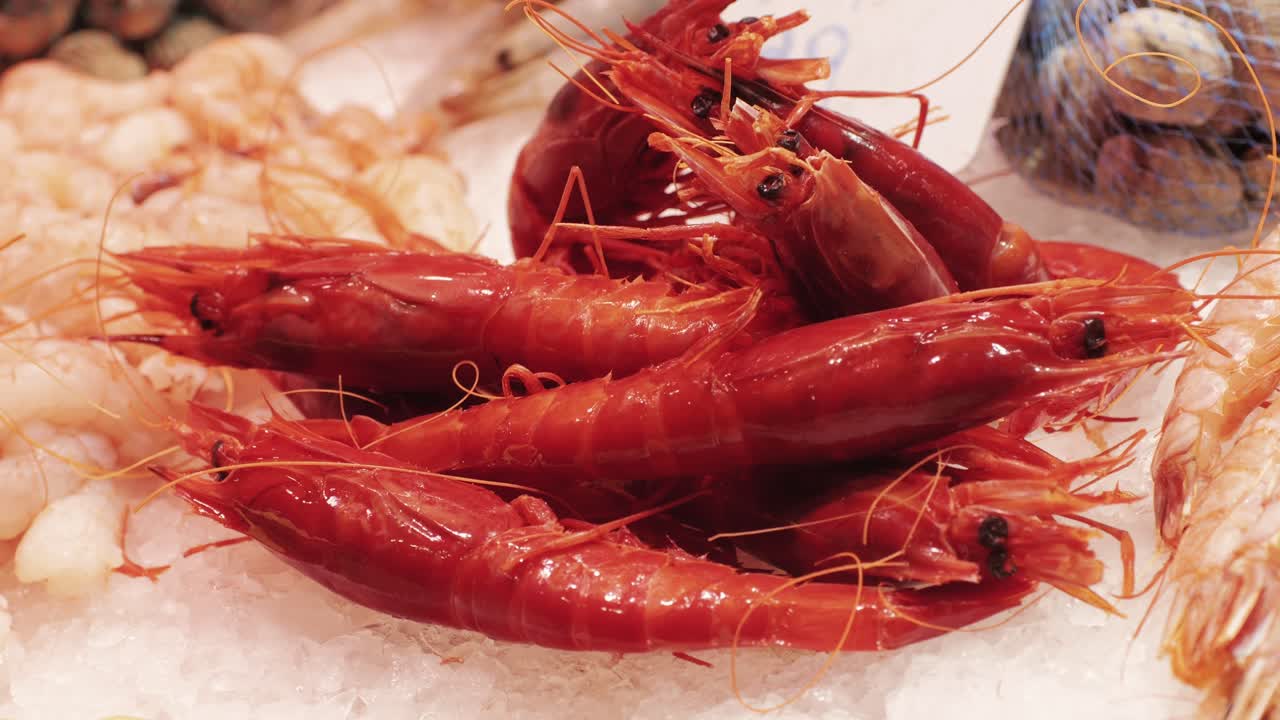Close-up of fresh red prawns displayed on ice at a seafood market, showcasing their vibrant color and freshness.
