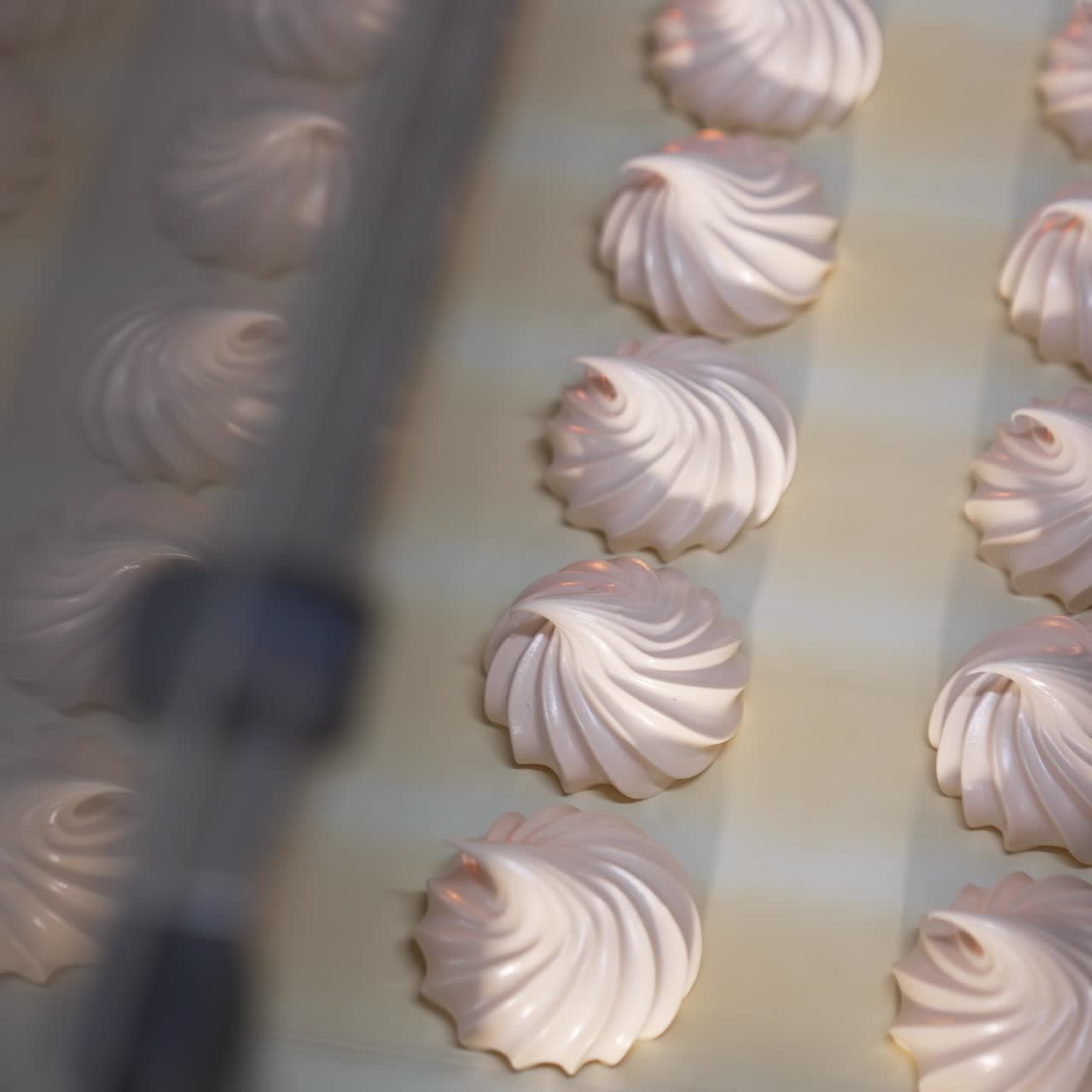Freshly-made vanilla zephyr desserts on the conveyor line. Marshmallow manufacturing at modern food factory. Close up. Top view