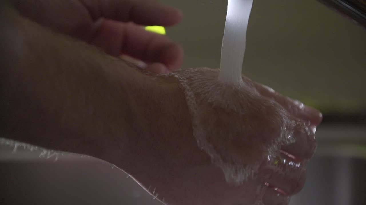 Prevenzione coronavirus. Primo piano di un uomo che si lava le mani con acqua corrente e sapone verde nel lavandino
