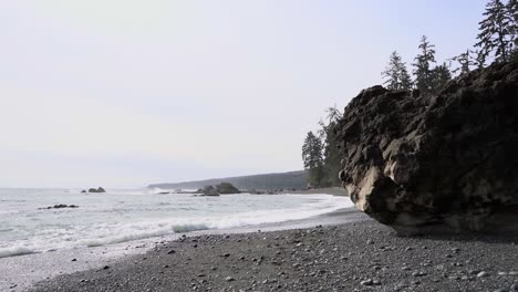 slow motion of sea waves hitting rugged sand shore near woodland on an overcast day, sombrio beach, british columbia, canada