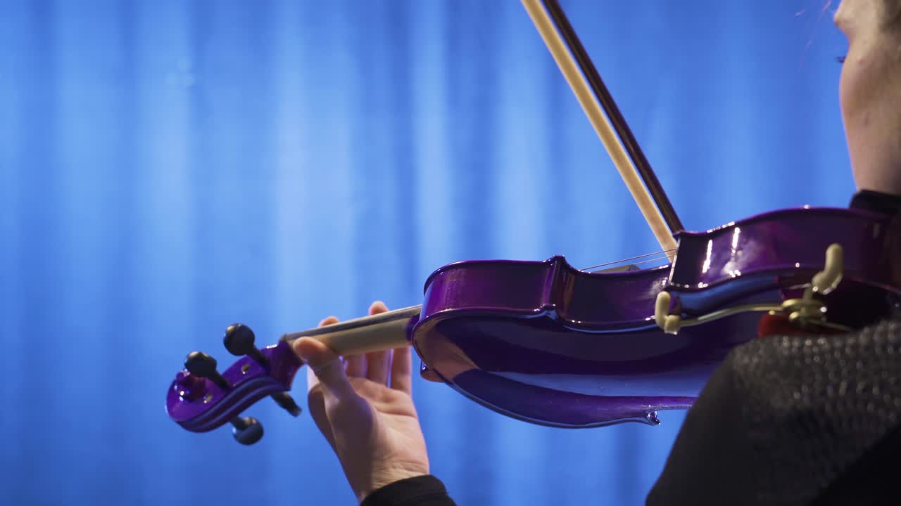 The female violinist plays the violin at the music school, the musician plays the violin at the opera.