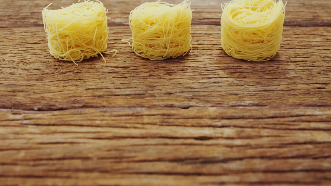 Tre nidi di spaghetti su tavolo di legno