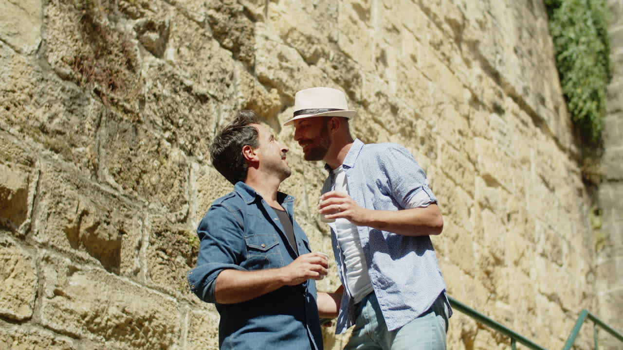 계단에서 키스하는 쾌활한 게이 커플의 정적 샷