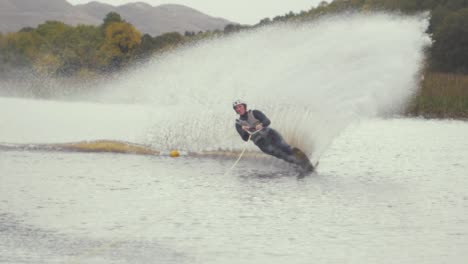 Mann-Slalom-Ski-Schneidet-Um-Boje-Wasserski-Zeitlupe