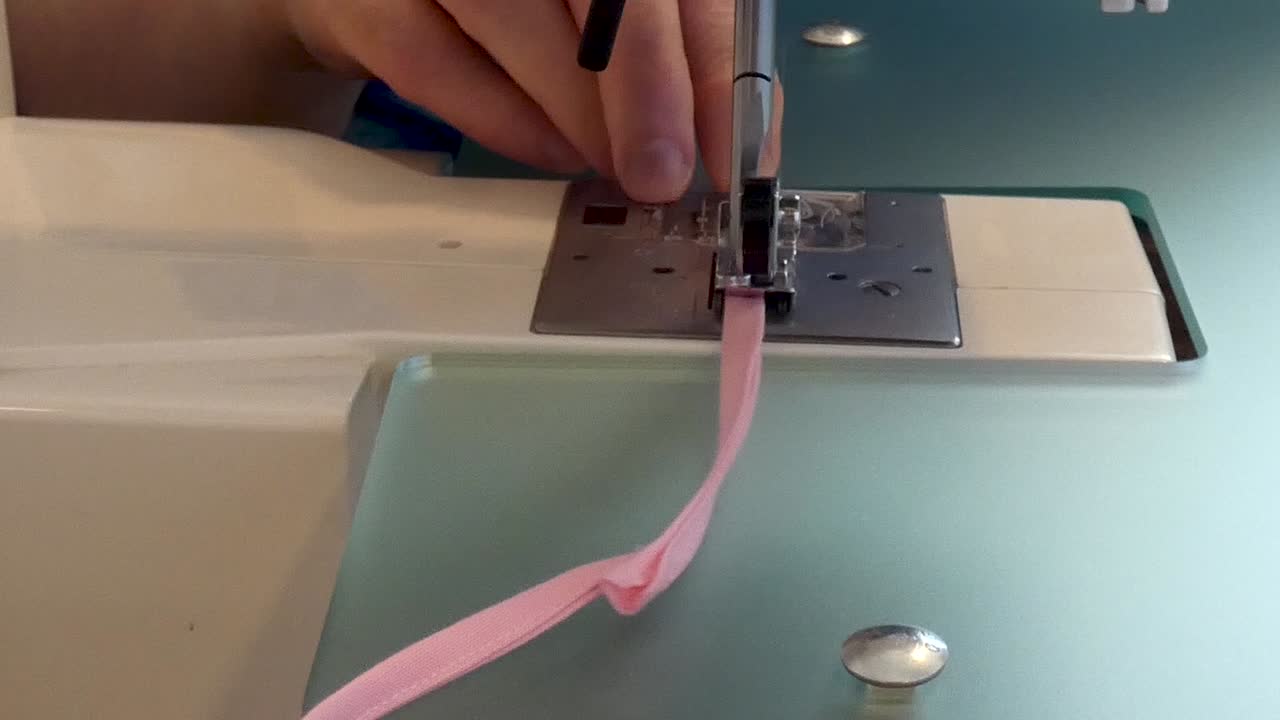 A woman top-stitches narrow strips of binding