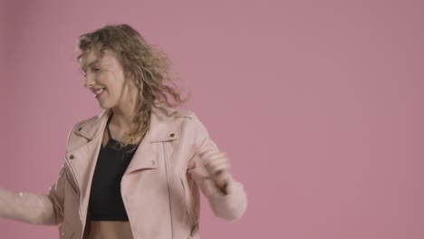 studio shot of young woman having fun dancing against pink background