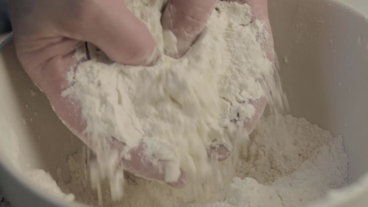 Hands mixing flour in a bowl close up isolated shot