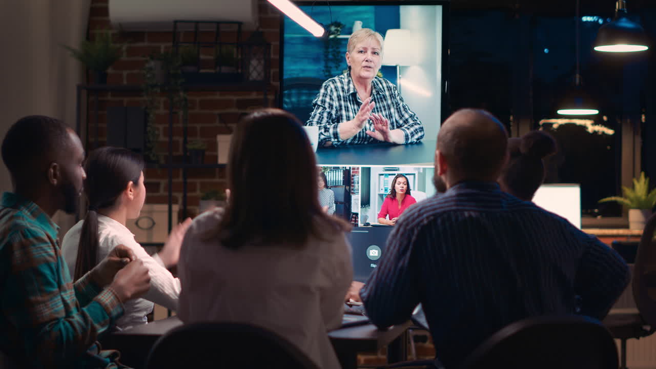 Employees greeting mid adult coworker in videocall, waving hi