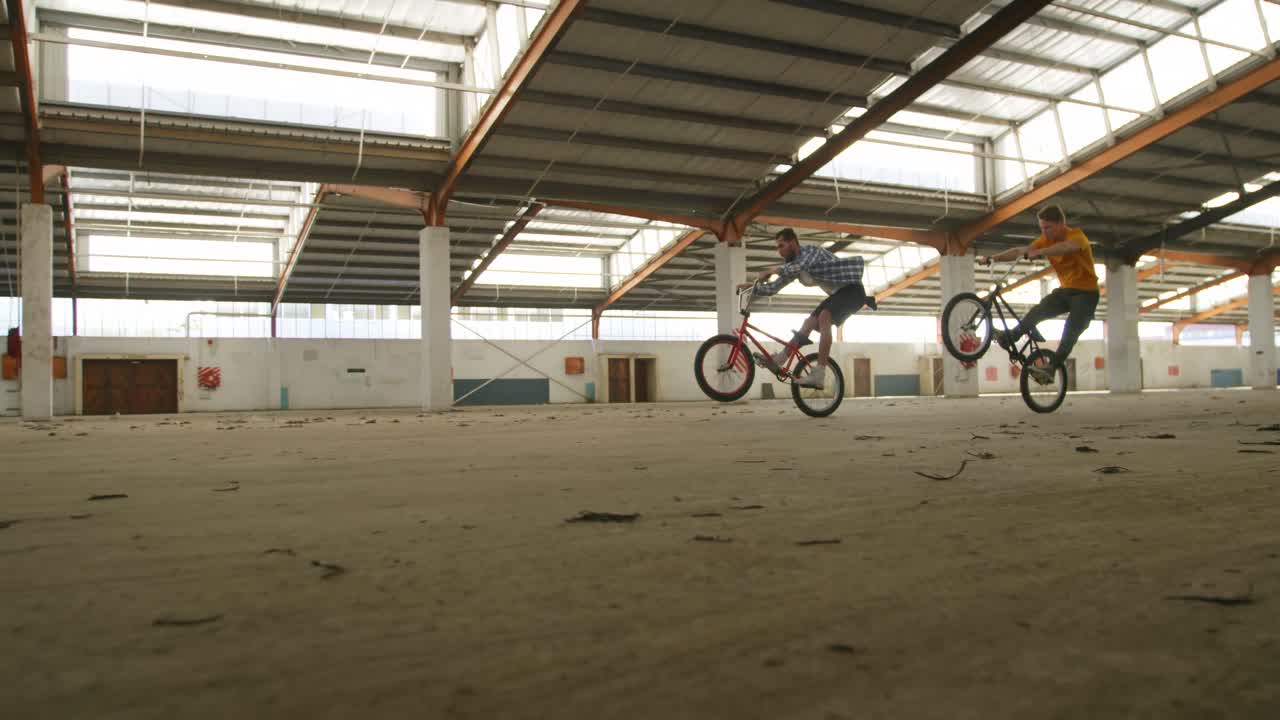 jinetes de bmx en un almacén vacío