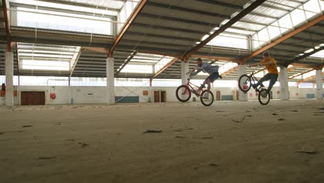 bmx riders in an empty warehouse