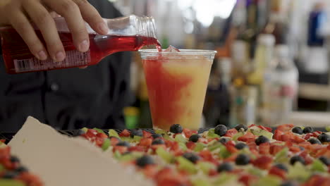 bartender mixing red and orange drink at bar