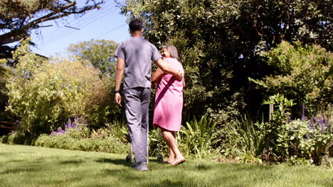 walking in garden, male physiotherapist supporting senior woman