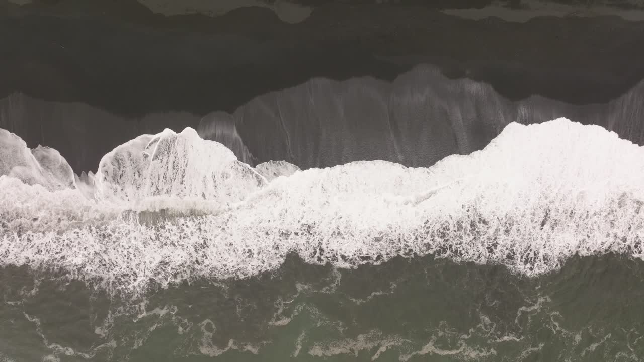 Aerial View of Waves Crashing on a Black Sand Beach