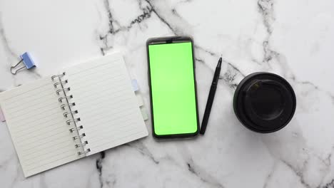 smartphone, notebook, pen, and camera lens on marble tabletop