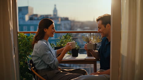 couple enjoying coffee on a balcony at sunset
