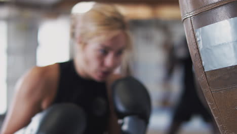 Boxerin-Im-Fitnessstudio-Trainiert-Mit-Altmodischem-Boxsack-Aus-Leder