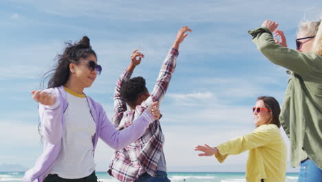 happy group of diverse female friends having fun, dancing and smiling at the beach