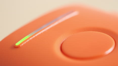 Orange-plastic-electronics-device-with-illuminated-flashing-power-charging-battery-indicator