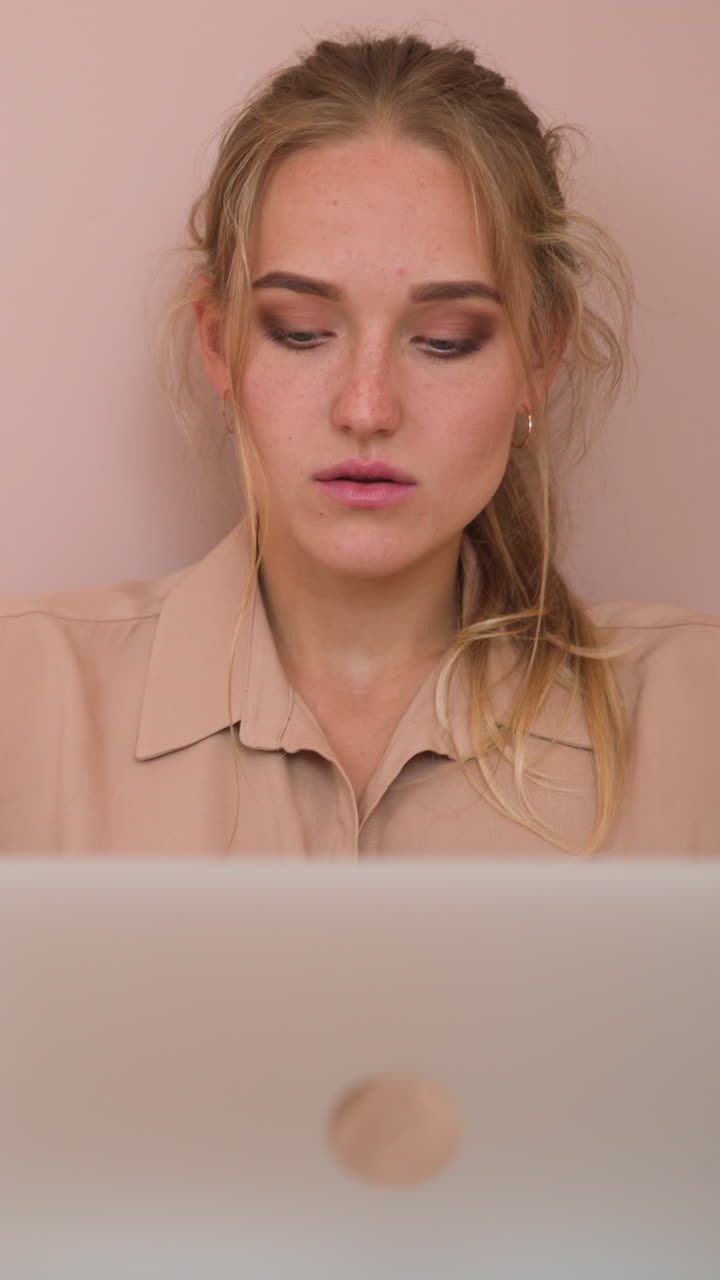 Young student woman in beige shirt writes senior thesis on modern laptop put on bed breakfast table sitting in soft bed at home slow motion