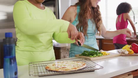 grupo diverso de felices amigas preparando pizza en casa